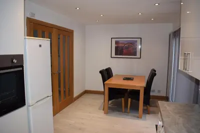 a kitchen with a table and chairs and a refrigerator at 3 Bedroom-Kelpies Serviced Apartments Bruce in Falkirk