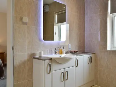 a bathroom with a white sink and a mirror at Liftingstane Cottage in Closeburn