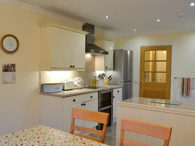 a kitchen with white cabinets and a table and chairs at Taigh Seonaig in Glencoe