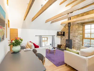 a living room with a table and a fireplace at The Hayloft in Blitterlees
