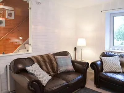 a living room with a leather couch and a chair at Craig Lora in Dalmally