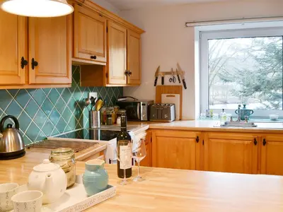 a kitchen with wooden cabinets and a bottle of wine on a counter at Craig Lora in Dalmally