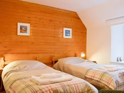 two beds in a room with wooden walls at Craig Lora in Dalmally