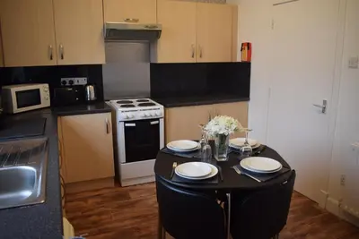 a kitchen with a table with plates and flowers on it at Kelpies Serviced Apartments McDonald- 2 Bedrooms in Falkirk
