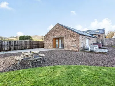 a brick building with a picnic table and a picnic table at Woodend Barn in Auchterarder