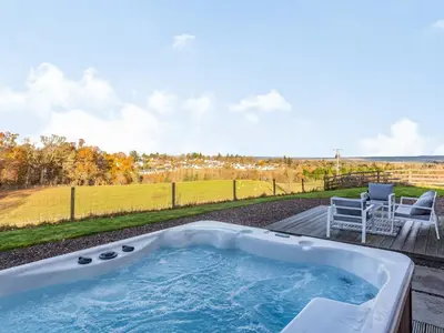 a hot tub on a patio with a table and chairs at Woodend Barn in Auchterarder