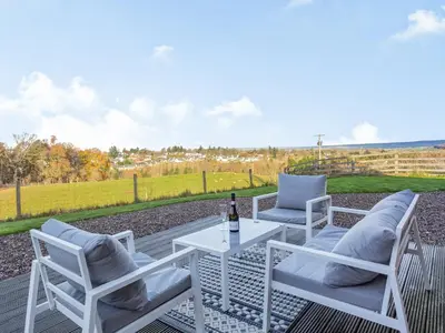 a patio with two chairs and a table with a bottle of wine at Woodend Barn in Auchterarder