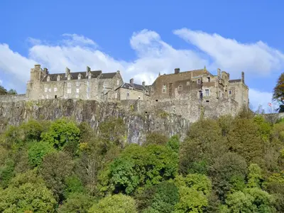 a castle on top of a hill with trees at Woodend Barn in Auchterarder