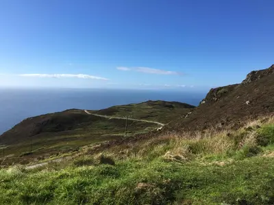 a road on a hill with the ocean in the background at The Carradale Hotel in Carradale