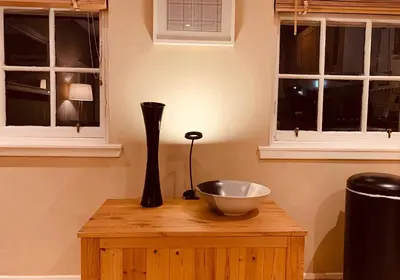a vase and a bowl on a wooden table with windows at The Webstersland Residence in Edinburgh