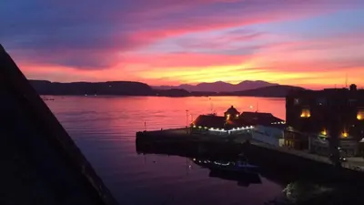 a sunset over a body of water with a pier at Argyll Mansions Penthouse in Oban
