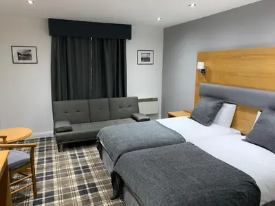 a hotel room with two beds and a couch at Crowwood Hotel and Alba Restaurant in Chryston