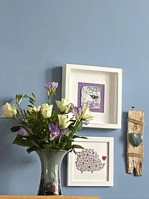 a vase with flowers on a table with pictures at Alpine cottage in Crieff