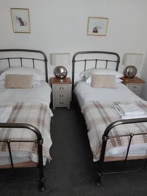 a bedroom with two beds and a night stand with two tables at Cladich House Bed & Breakfast in Cladich