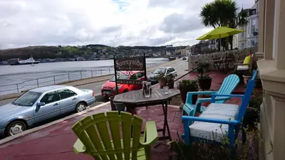 a patio with chairs and a table and a car at Sunnyside House in Rothesay