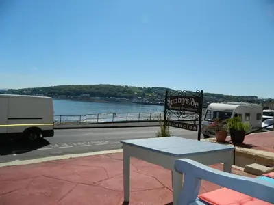 a table and chairs on a patio with a view of the water at Sunnyside House in Rothesay