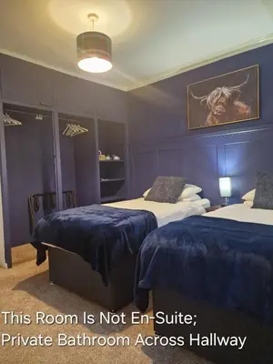 a hotel room with two beds with blue sheets at The White Stag Inn in Strathyre