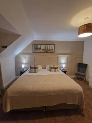 a bedroom with a large bed and a chair at The White Stag Inn in Strathyre