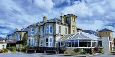 a large house with a conservatory in front of it at Fairfield House Hotel in Ayr