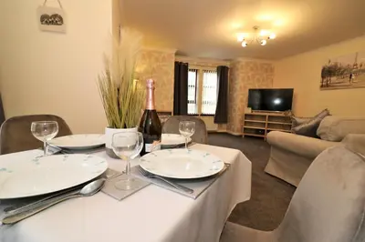a living room with a table with a bottle of wine at Signature - Douglas View Blantyre in High Blantyre