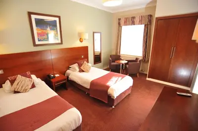 a hotel room with two beds and a table at Golden Lion Hotel in Stirling