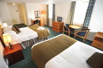 a hotel room with two beds and a table and chairs at Golden Lion Hotel in Stirling