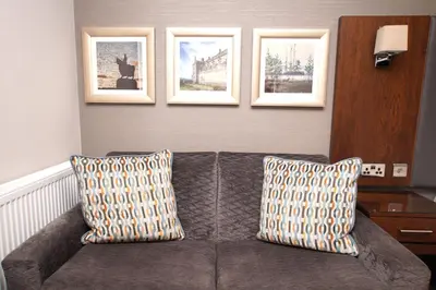 a couch in a living room with three pictures on the wall at Golden Lion Hotel in Stirling
