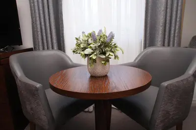 a vase of flowers on a wooden table with chairs at Golden Lion Hotel in Stirling