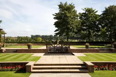 a park with a bench and grass and flowers at Western House Hotel At Ayr Racecourse in Ayr