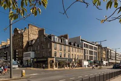 a busy city street with buildings on a sunny day at Destiny Scotland - Chisholm Hunter Suites in Edinburgh