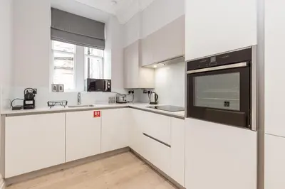 a white kitchen with white cabinets and a microwave at Destiny Scotland - Chisholm Hunter Suites in Edinburgh