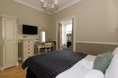 a bedroom with a bed and a desk and a television at The Haymarket Hotel in Edinburgh