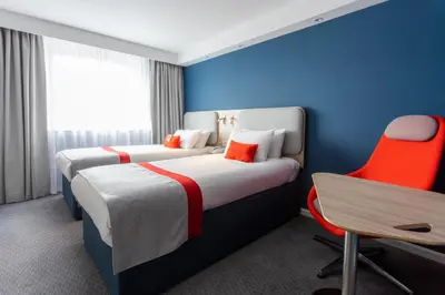 a hotel room with two beds and a chair at Holiday Inn Express - Glasgow - City Ctr Theatreland by IHG in Glasgow