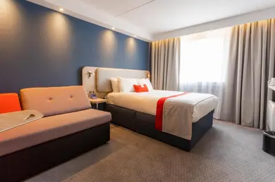 a hotel room with a bed and a chair at Holiday Inn Express - Glasgow - City Ctr Theatreland by IHG in Glasgow