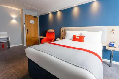 a hotel room with a large bed and a red chair at Holiday Inn Express - Glasgow - City Ctr Theatreland by IHG in Glasgow