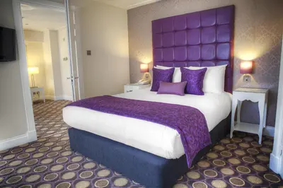 a large bed with a purple headboard in a hotel room at Holiday Inn - Glasgow - City Ctr Theatreland by IHG in Glasgow