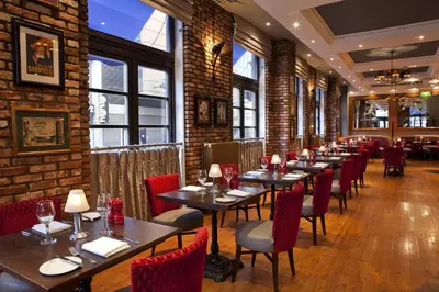 a row of tables in a restaurant with red chairs at Holiday Inn - Glasgow - City Ctr Theatreland by IHG in Glasgow