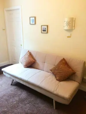 a white couch with two pillows on it in a room at Commodore Guesthouse, Seaside Holiday Suites in Rothesay
