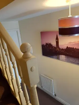 a staircase with a picture of a clock tower on the wall at Livingston 4 bedroom townhouse in Livingston