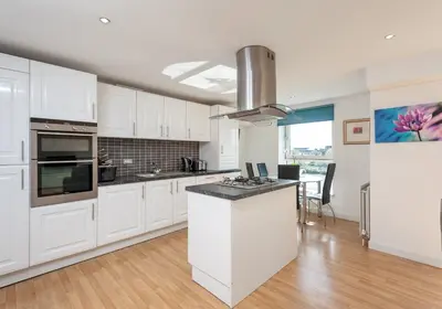 a kitchen with white cabinets and a counter top at The Metropole Residence in Glasgow
