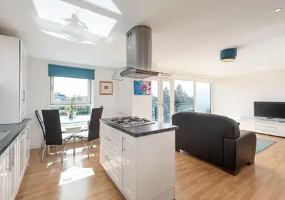 a kitchen and living room with a stove and a table at The Metropole Residence in Glasgow