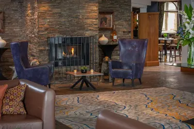a living room with chairs and a fireplace at Glasgow Westerwood Hotel, Spa & Golf Resort in Cumbernauld