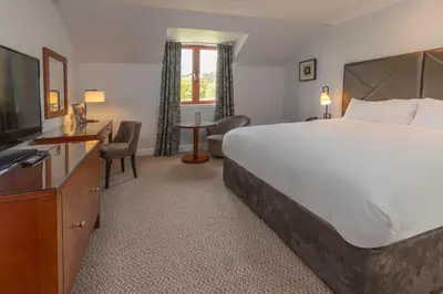 a hotel room with a large bed and a television at Glasgow Westerwood Hotel, Spa & Golf Resort in Cumbernauld