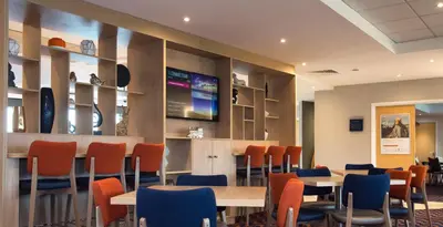 a waiting room with tables and chairs and a tv at Holiday Inn Express Dunfermline by IHG in Dunfermline