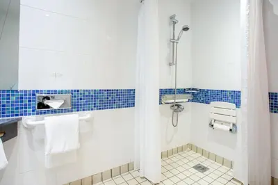 a bathroom with a shower with blue tiles at Holiday Inn Express Dunfermline by IHG in Dunfermline