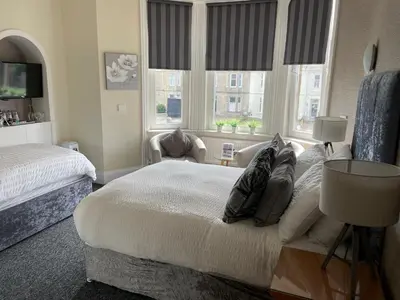 a bedroom with a large bed and two windows at Beechwood Ensuite Guest House in Ayr
