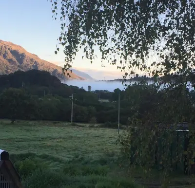 a view of a field with fog in a valley at Curacao Caravans in Taynuilt