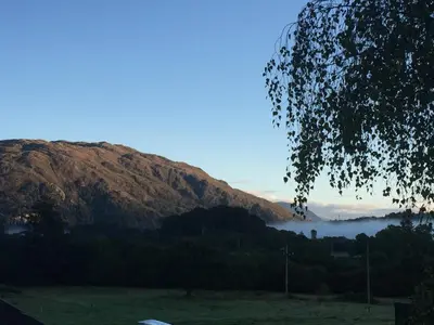 a view of a mountain with fog in a field at Curacao Caravans in Taynuilt