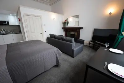 a bedroom with a bed and a couch and a television at Grosvenor Suites in Edinburgh