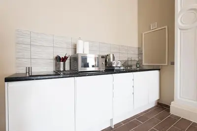 a kitchen with white cabinets and a microwave at Grosvenor Suites in Edinburgh